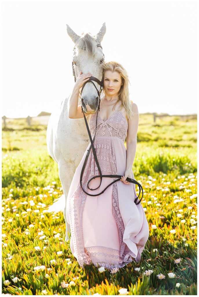 Woman in beautiful dress holding white horse