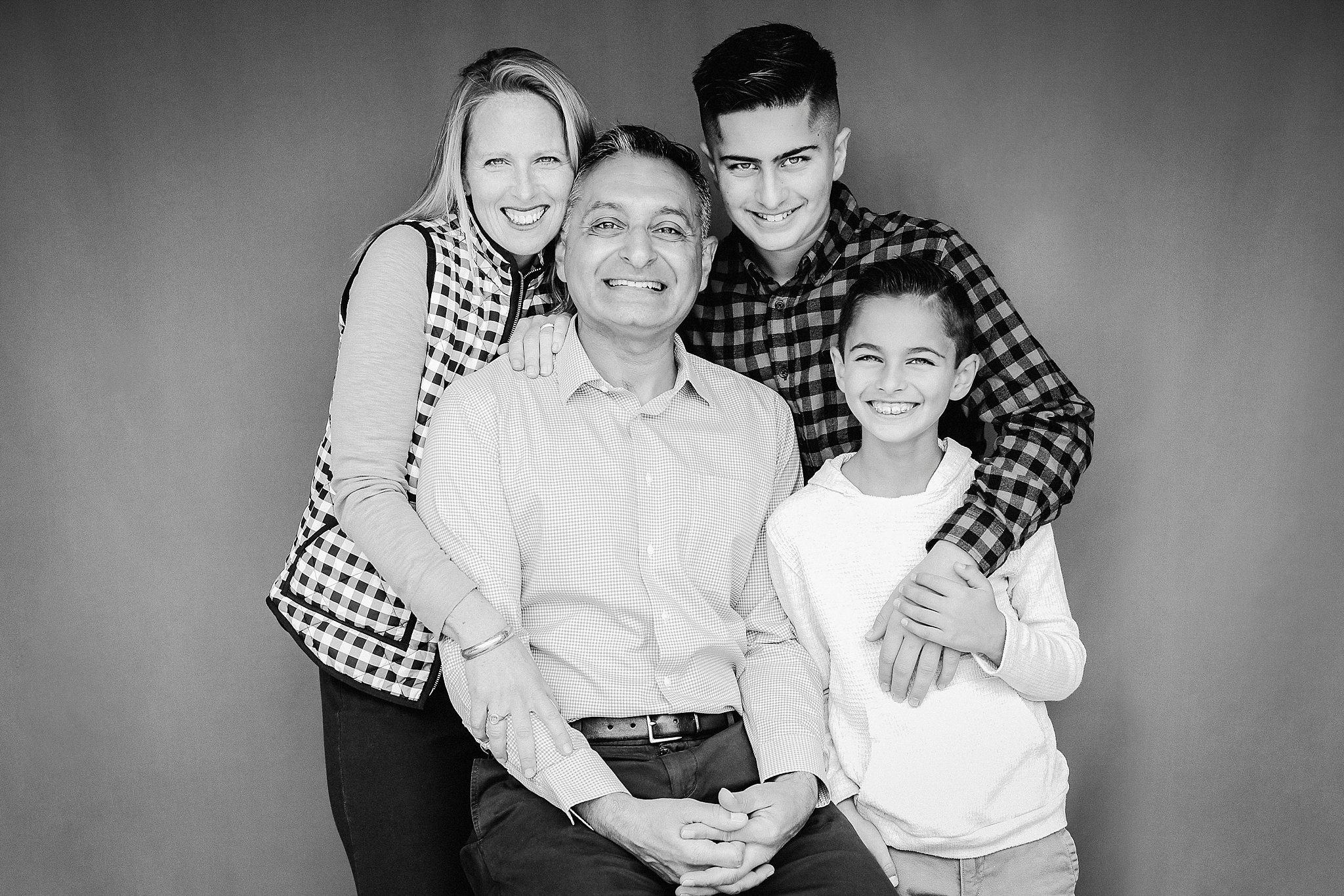 Family of four sharing a close black-and-white studio portrait in San Jose